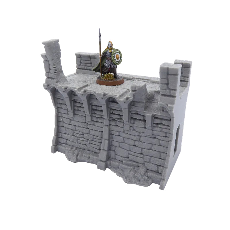 Model of a stone wall with a figurine on top against a white background
